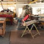 Goldener Relaxdays Sägebock mit roter Kettensägenhalterung und Holzstamm.