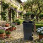 Manuelle Relaxdays Müllpresse aus Stahl auf grauer Mülltonne im Garten. Komprimiert Abfall, spart Platz.