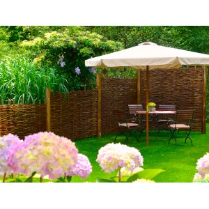 T & J Weidengeflechtzaun Aso als Sichtschutz im Garten mit Sitzgruppe unter Sonnenschirm.