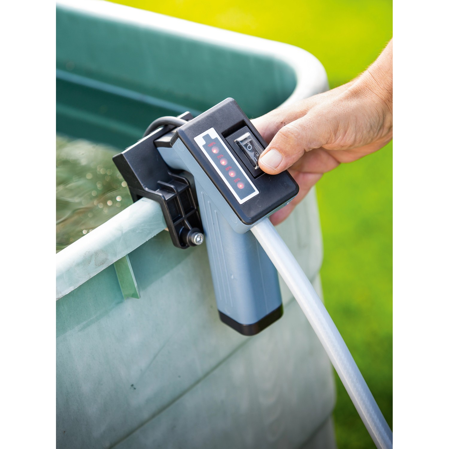 Akku-Regenfasspumpe (50 W) am Regenfass im Einsatz. Elektro-Pumpe mit Bedienfeld und Schlauch.