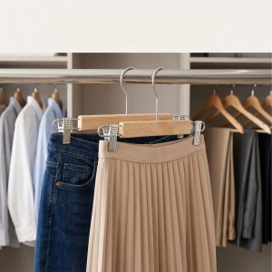 Hosenbügel Set aus Naturholz und Metall mit Jeans und Rock im Kleiderschrank. Gummierte, verstellbare Clips.