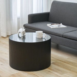 Schwarzer runder Beistelltisch aus Paulownia Holz mit Rattanoptik und Glasplatte im Wohnzimmer.