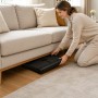 Frau verstaut schwarzen Relaxdays Puzzlekoffer mit Tragegriff unter Sofa. Praktische Puzzleunterlage.