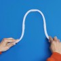 Flexibler WiZ LED Strip (3m) in Weiß, der von Händen vor blauem Hintergrund gebogen wird.