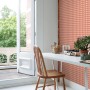 ESTAhome Tapete mit terrakottarosa Karomuster an einer Wand in hellem Raum mit weißem Schreibtisch und Stuhl.