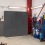 Anthrazitfarbener Rikta Metallschrank (168x80x40cm) mit Flügeltüren und vier Einlegeböden im Werkstatt-Umfeld.