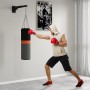 Schwarze Boxsack Wandhalterung mit trainierendem Mann und Boxsack. Ideal für das Boxtraining zu Hause.