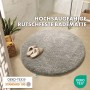 Runde, flauschige, ivoryfarbene KARAT Badematte (Ø 95cm) mit Hausschuhen im Badezimmer.