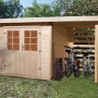 OBI Holz-Gartenhaus La Spezia mit Anbaudach, Fahrrädern und Gartengeräten im Garten.