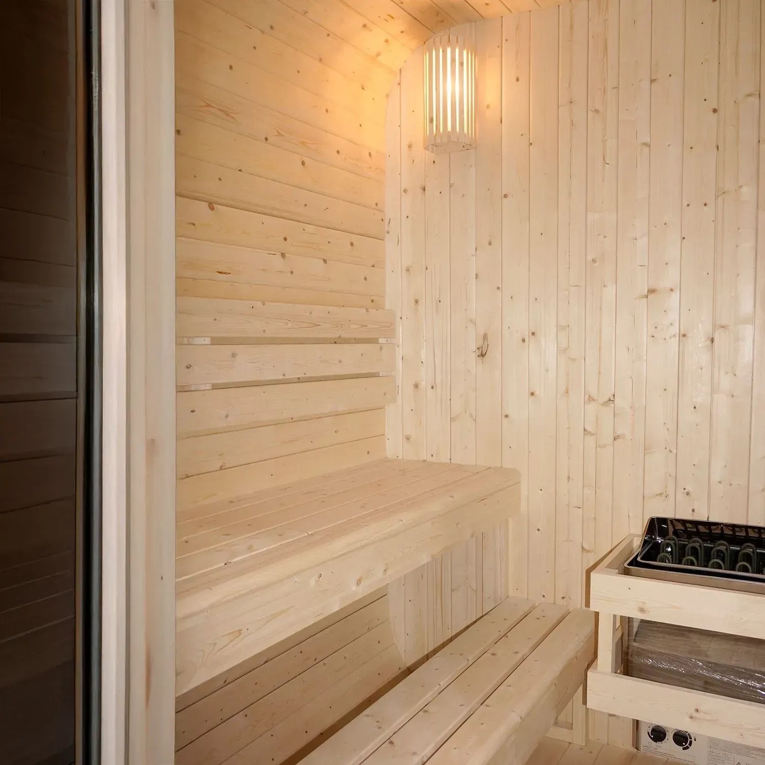 Innenansicht Artsauna Cube Fasssauna Fjora mit Holzverkleidung, Bänken und Saunaofen.