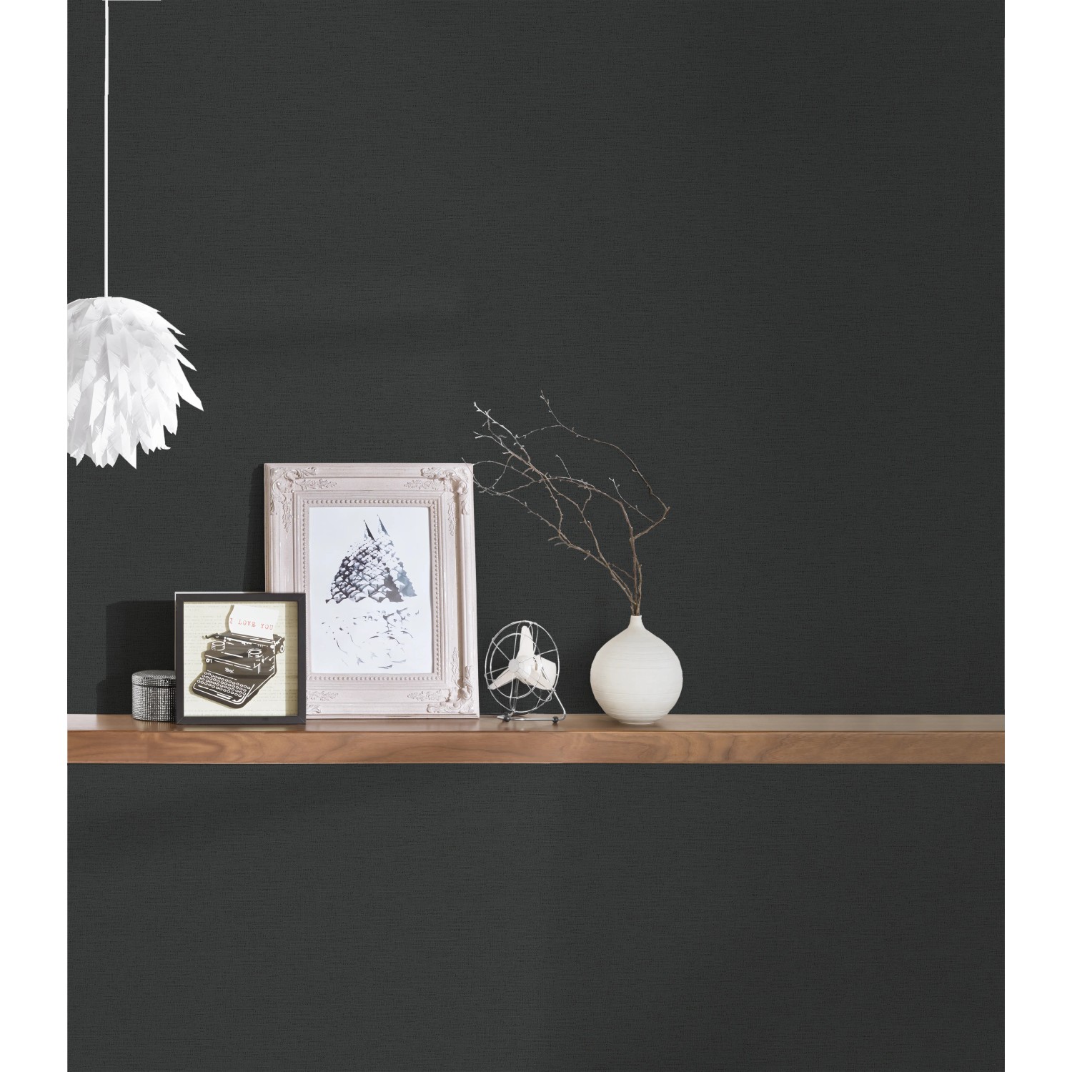 Schwarze Vliestapete Uni von Trendwall 2, kombiniert mit Deko-Elementen auf einem Holzregal.