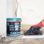 Soudal Fix All Floor & Wall Kleber im Eimer mit Zahnspachtel in Anwendung.