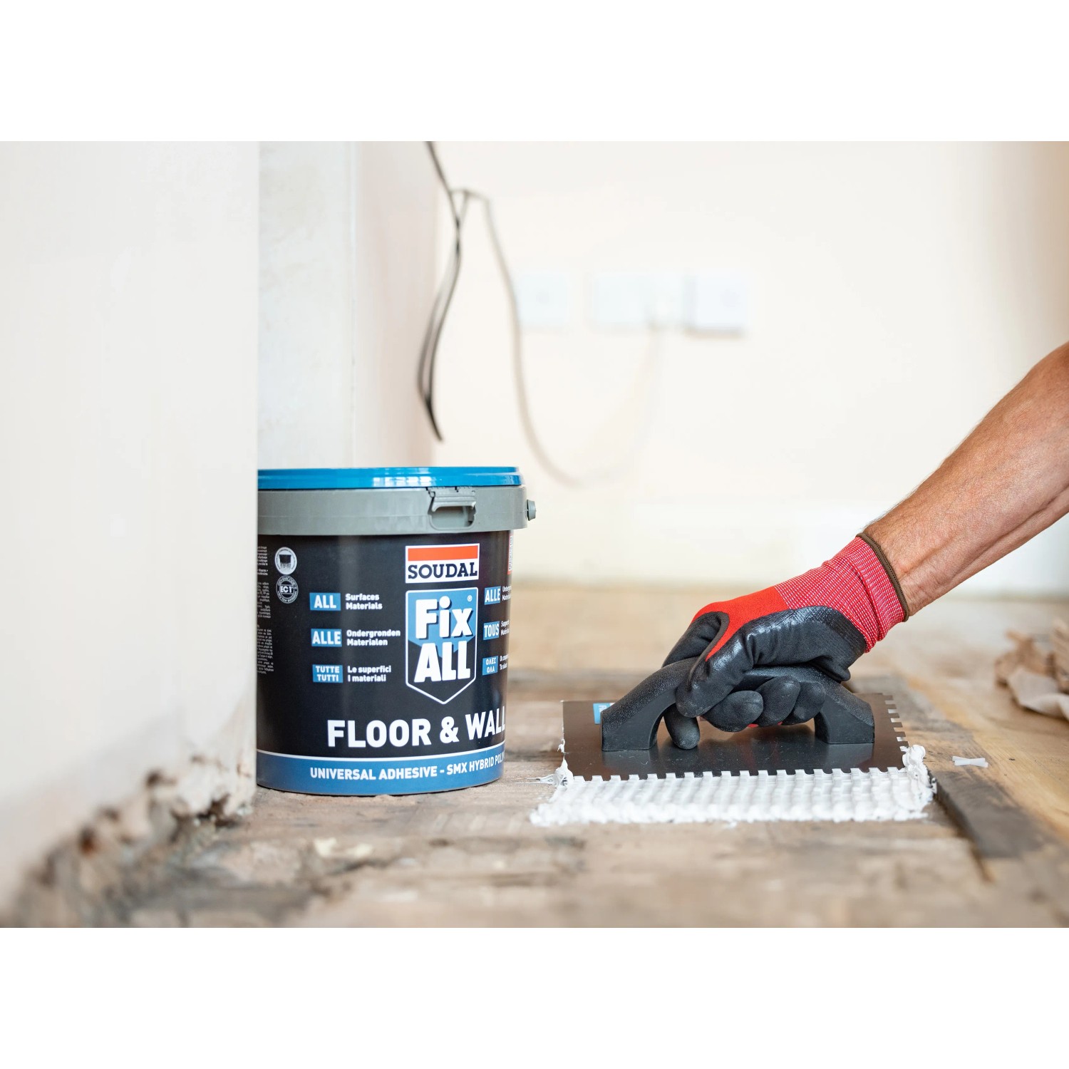 Soudal Fix All Floor & Wall Kleber im Eimer mit Zahnspachtel in Anwendung.