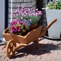 Dekorative, dunkelbraune Pflanz-Schubkarre aus Holz, bepflanzt mit bunten Blumen.