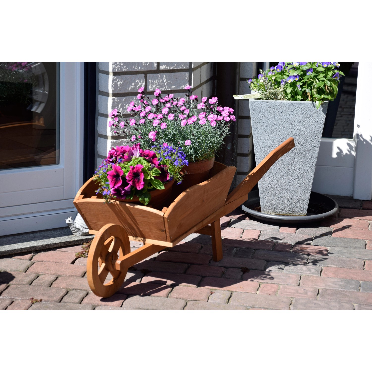 Dekorative, dunkelbraune Pflanz-Schubkarre aus Holz, bepflanzt mit bunten Blumen.