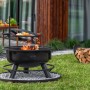 Schwarze CookKing Feuerschale Bandito mit Grillrost und Zubehör im Garten.