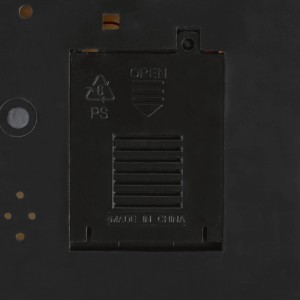 Rückseite der beleuchteten Weihnachtsdorf Szene: schwarzes Batteriefach aus Kunststoff mit 'OPEN' Aufschrift und PS-Symbol.