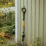 Fiskars Unkrautstecher X-Series, orange-schwarz, an einer Wand hängend.
