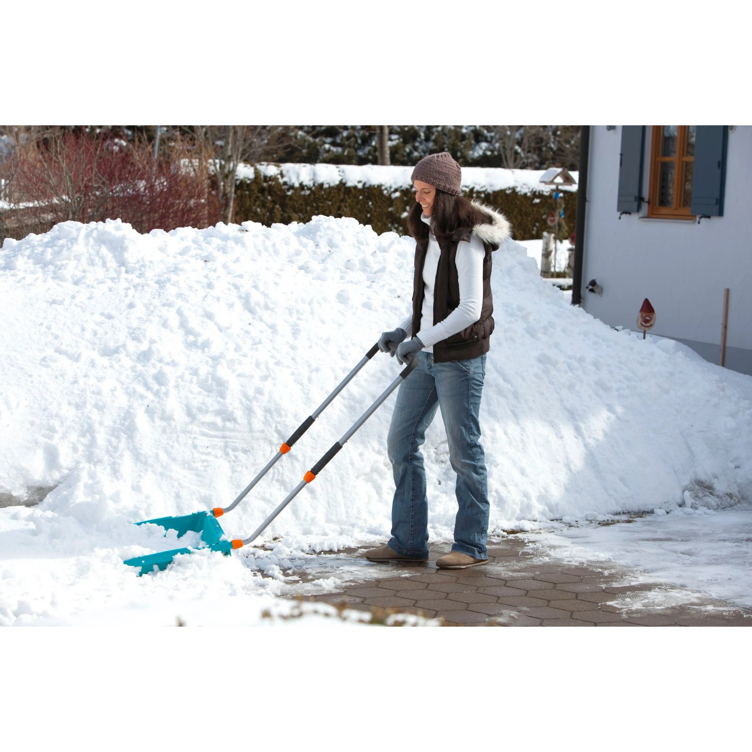Frau schiebt Schnee mit Gardena Schneewanne 70 cm. Schneeschieber mit Stahlkante.
