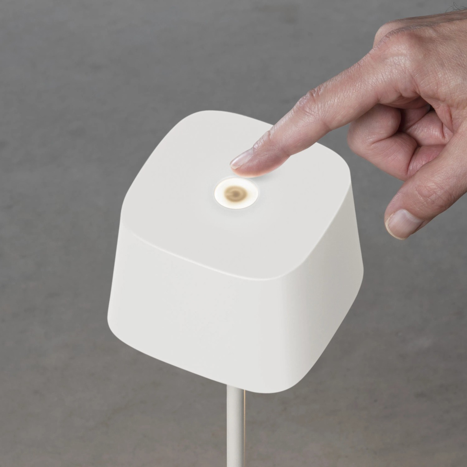 Weiße Konstsmide LED Tischleuchte Capri mit Finger auf dem Touch-Sensor. Außen-Dekoleuchte, dimmbar.