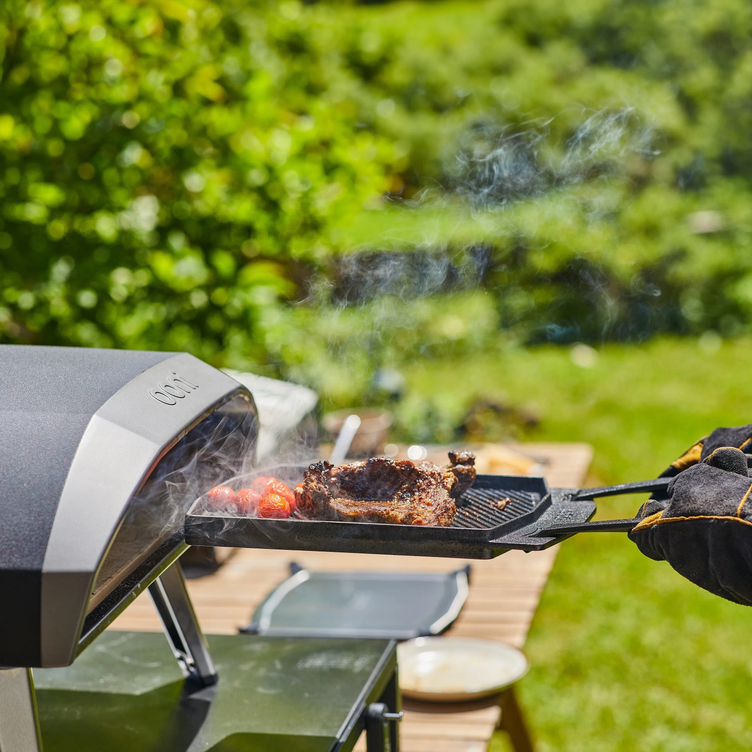 Ooni Grillpfanne Dual-Sided Grizzler mit Steak und Gemüse am Grillofen.
