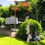 Dunkelgrüner Stahl Rankobelisk, 200 cm, mit Kletterpflanzen im Garten. Robuste Rankhilfe für Rosen und Clematis.