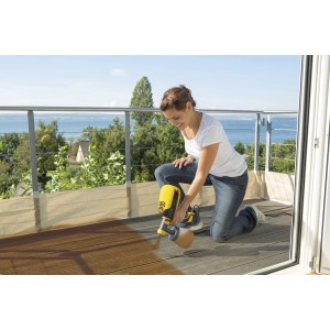 Frau sprüht mit Wagner Farbsprühsystem W 590 Holzterrasse. Sprühgerät in Gelb/Schwarz.