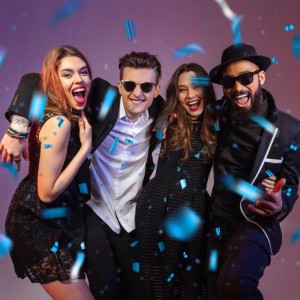 Vier lachende Personen feiern ausgelassen unter blauem Konfetti. Perfekt für Party, Geburtstag, Hochzeit mit Konfettikanone.