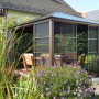 Bronzefarbener Sojag Aluminium Pavillon Castel 12x14 mit Moskitonetz und Schiebetüren im Garten.
