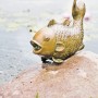 Heissner Teichfigur "Großer Fisch" aus Polyresin, kupferfarben, als Wasserspeier auf einem Stein.