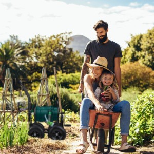 Schwarzer Relaxdays Gartenschlauchwagen aus Metall mit 4 Rädern und grünem Schlauch im Garten, während eine Familie gärtnert.