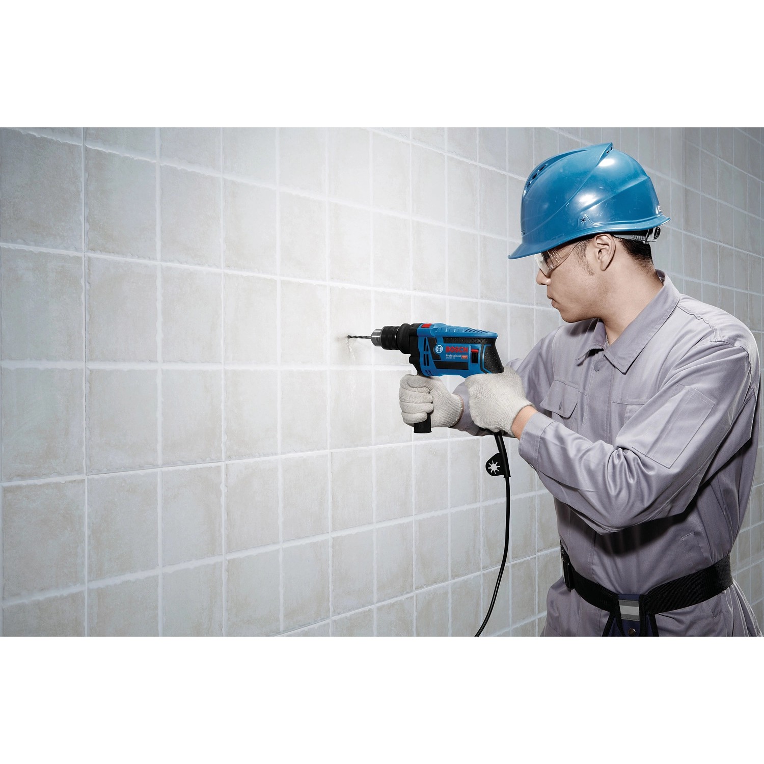 Mann bohrt mit Bosch Professional Schlagbohrmaschine GSB 13 RE in Fliesenwand.