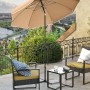 Taupefarbener Songmics Sonnenschirm (Ø 160 cm) auf einer Terrasse mit Gartenmöbeln.