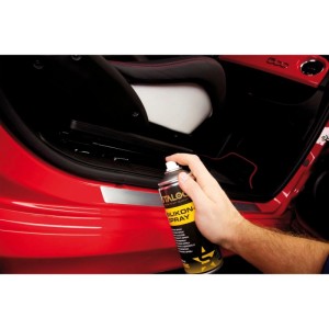 Hand sprüht Staloc Silikonspray auf rote Autotürdichtung. Schmiermittel für Gummi, Kunststoff & Metall. 400 ml.
