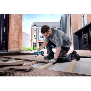 Mann verschraubt Terrassendielen mit blauem Akku-Drehschlagschrauber GDR 18V-215 Sol. Handwerker bei Bauarbeiten im Freien.