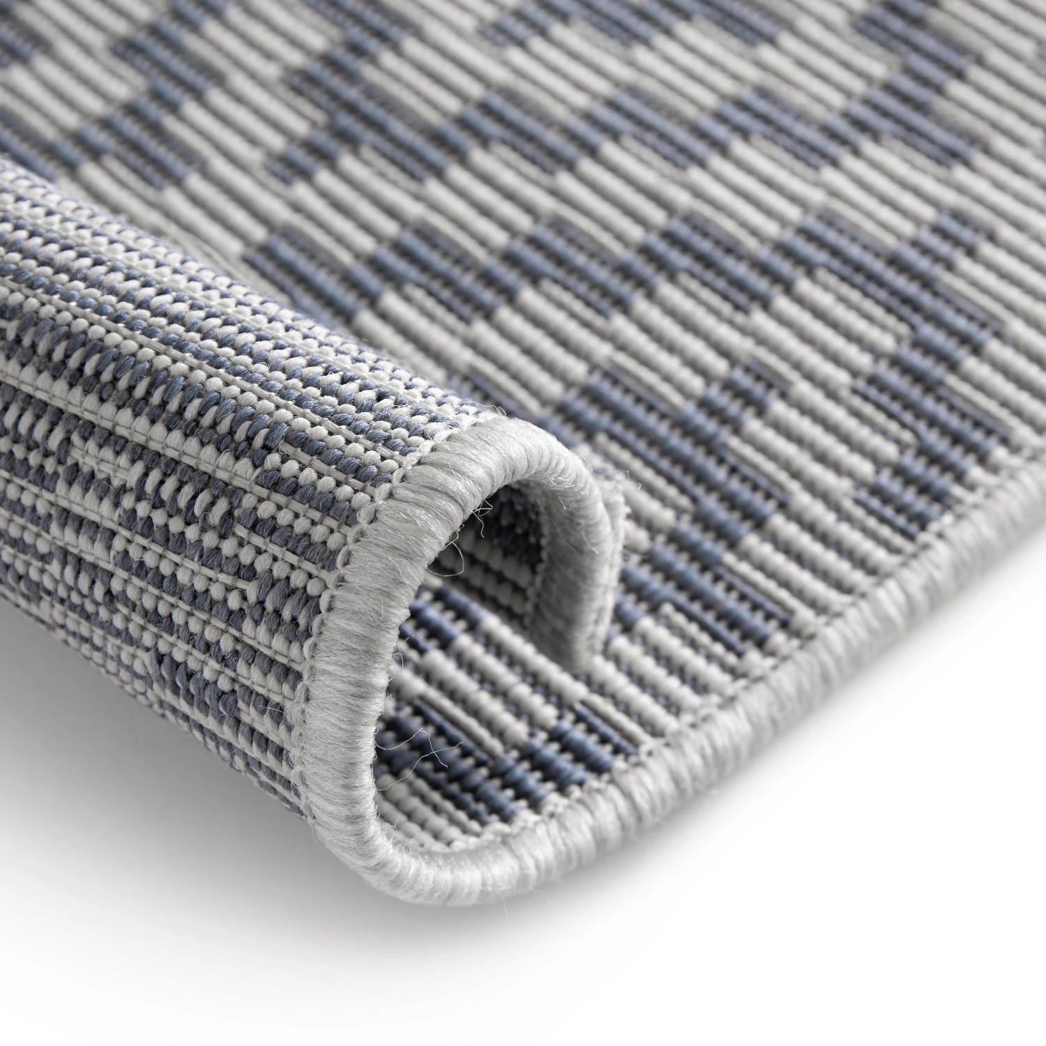 Detailansicht: Grau-blauer Primaflor Outdoorteppich Eldorado Quadra, gerollt.