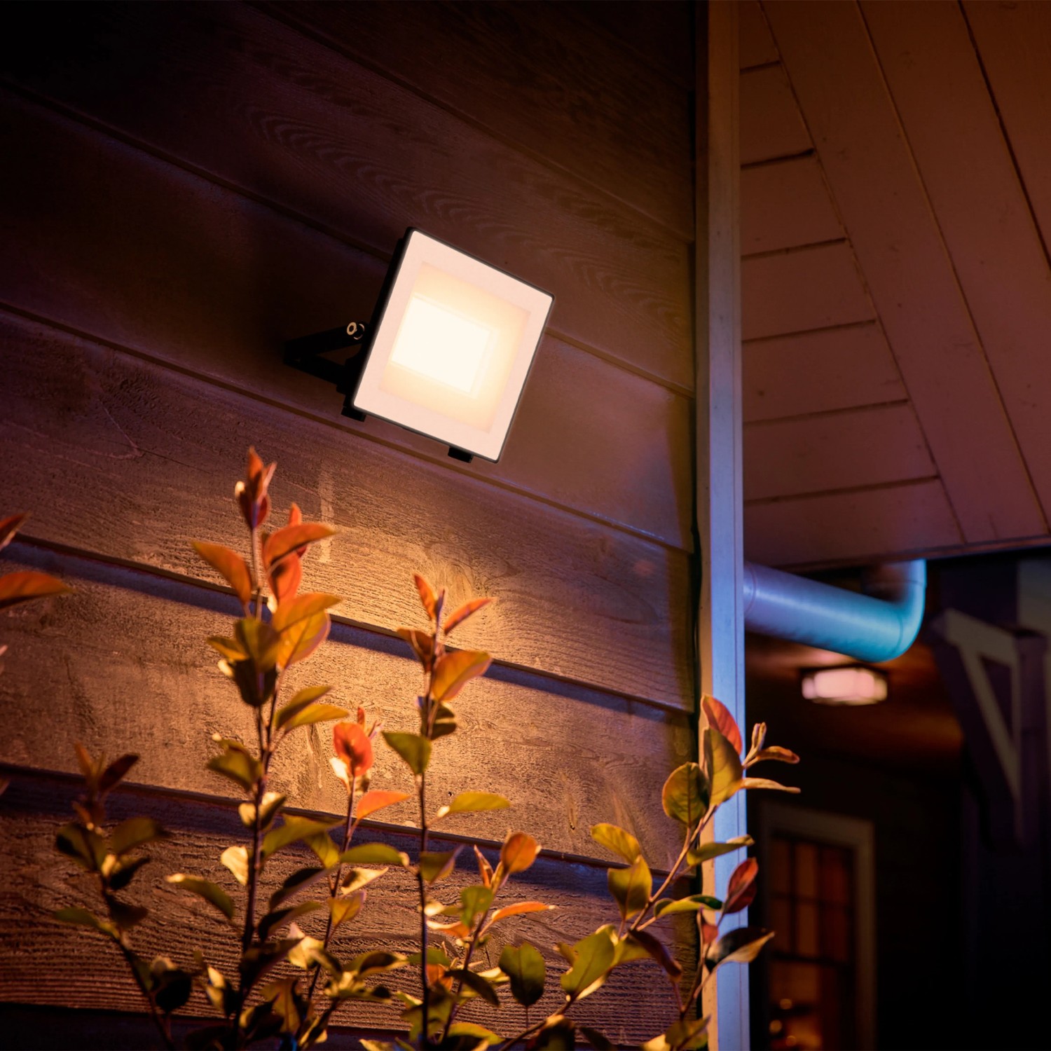 Anthrazitfarbener Philips LED-Außenstrahler Lois mit warmweißem Licht an einer Hauswand.