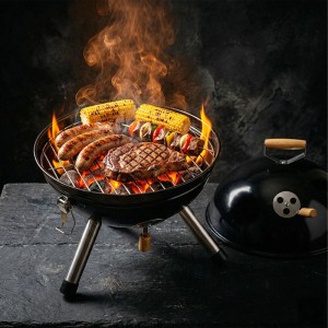 Schwarzer Relaxdays Holzkohlegrill mit Würstchen, Steak, Mais und Spieß auf dem Rost. Tragbarer Kugelgrill in Aktion.