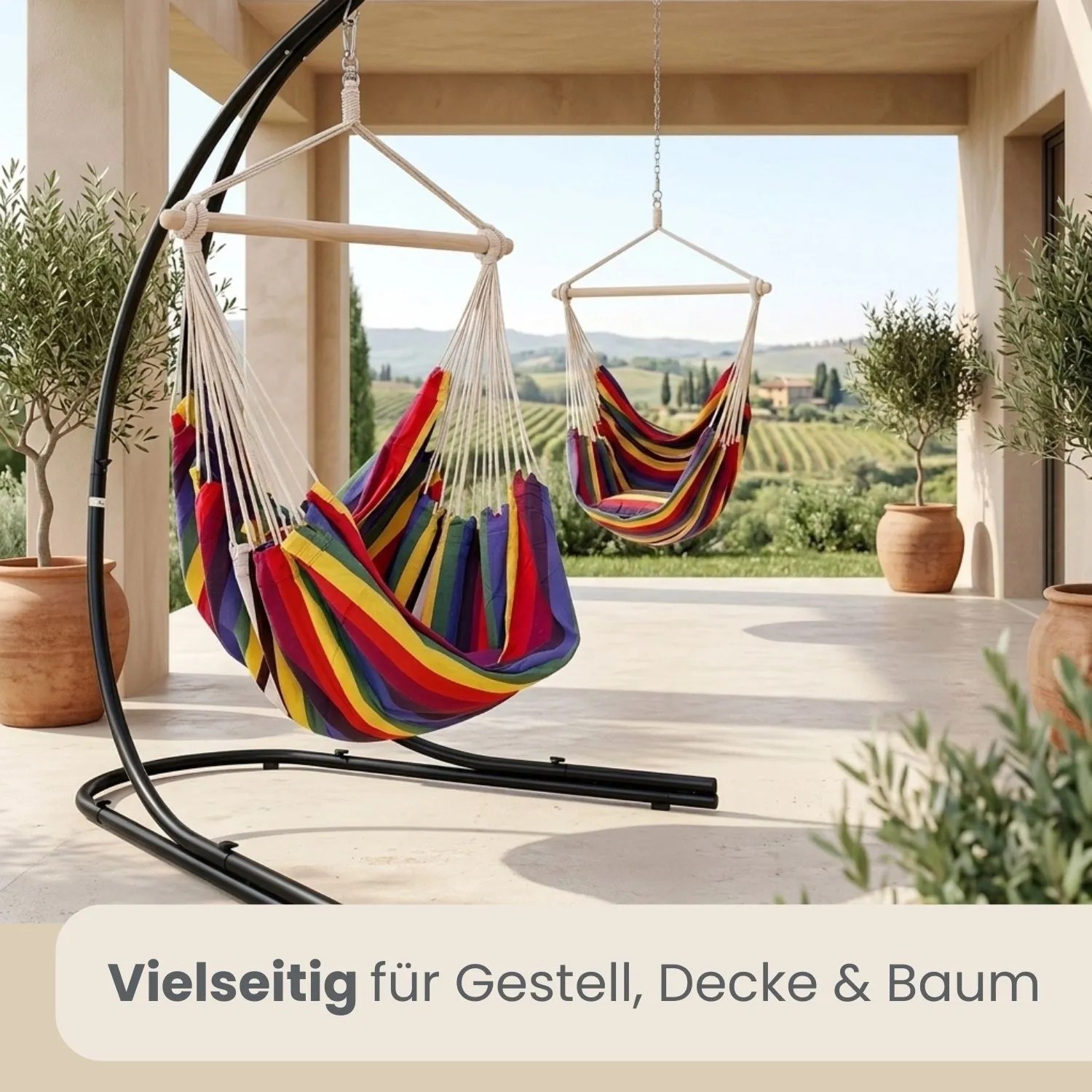Zwei AMANKA Hängesessel in Regenbogenfarben auf Terrasse. Einer am Gestell, einer von Decke hängend. Ideal für Garten & Balkon.