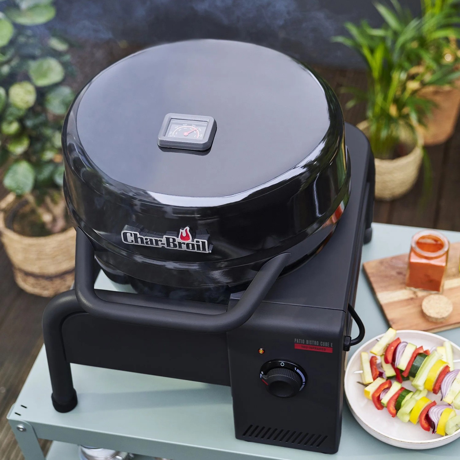 Schwarzer Char-Broil Elektrogrill Patio Bistro Cube E mit Gemüse-Spießen.