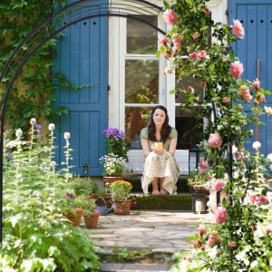 Schwarzer Relaxdays Rosenbogen aus Eisen, 216 cm hoch, mit blühenden Rosen und Frau im Garten.