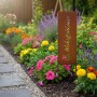 Rostbrauner Gartenstecker aus Eisen mit "Wohlfühloase" Schriftzug und Lotusblume im bunten Blumenbeet.