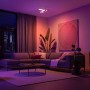 Philips Hue Centris Cross LED-Deckenleuchte mit 3 Spots in Weiß im Wohnzimmer mit farbiger Beleuchtung.