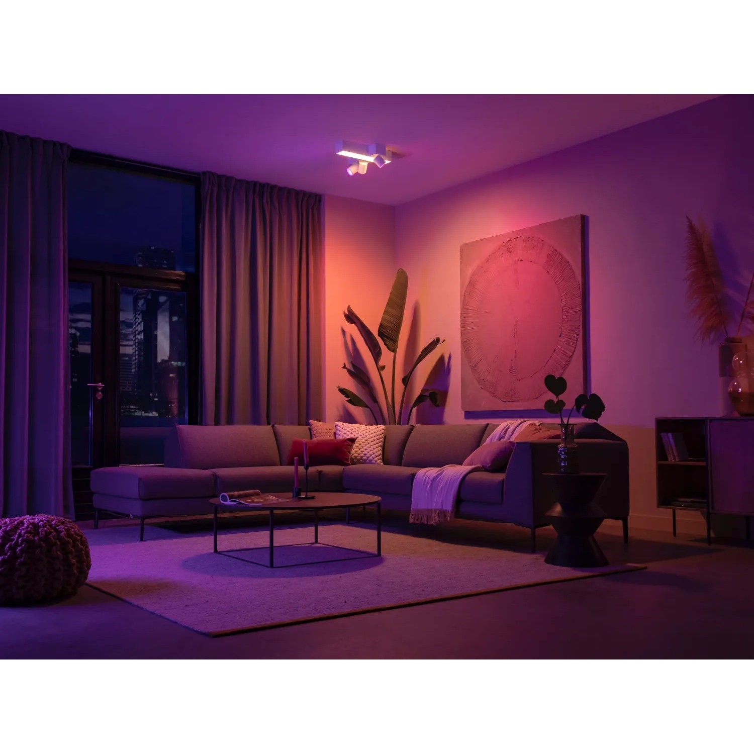 Philips Hue Centris Cross LED-Deckenleuchte mit 3 Spots in Weiß im Wohnzimmer mit farbiger Beleuchtung.