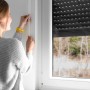 Frau befestigt weißen Schellenberg Rollladengurt Maxi (23mm, 6m) am Fenster.