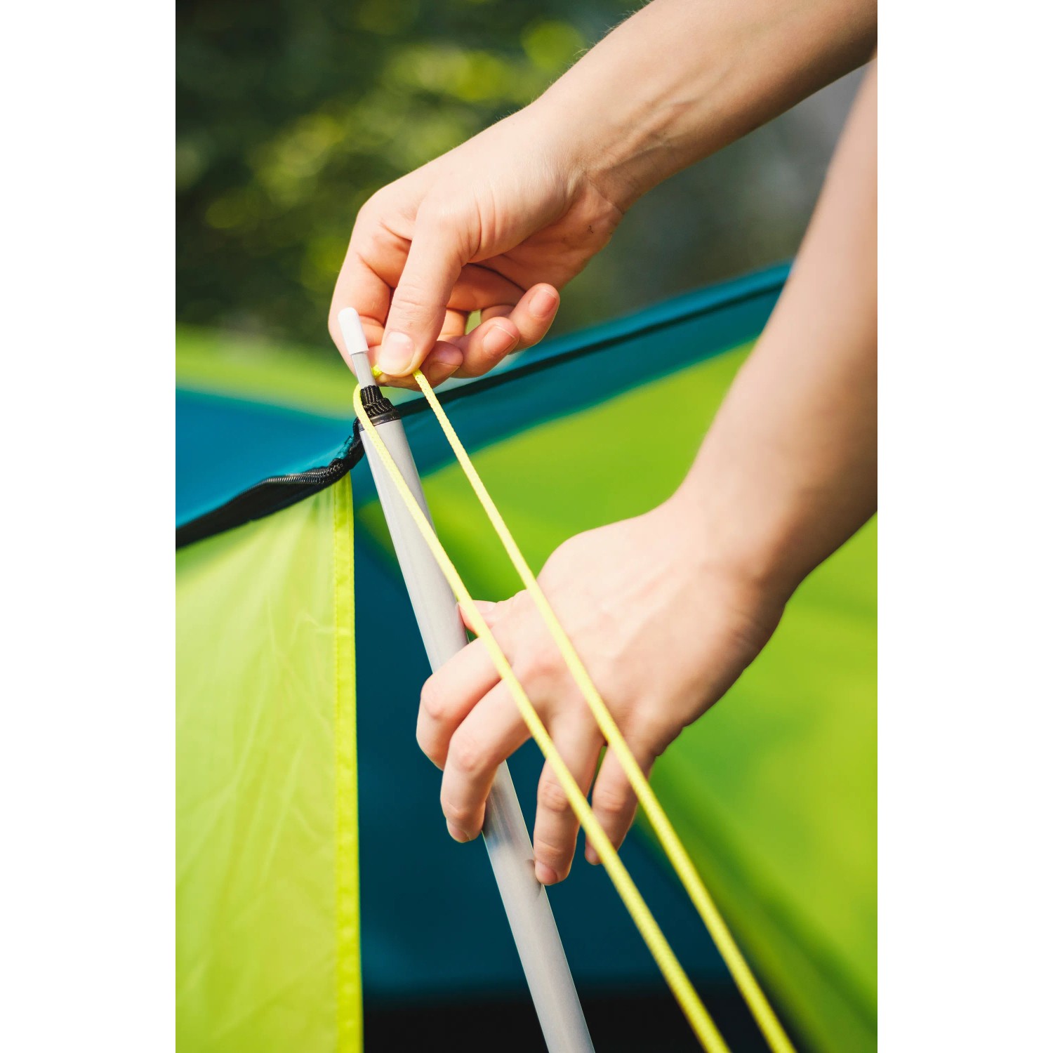 Aufbau des Bestway Cool Ground 3 Zeltes: Person befestigt Spannseil am Fiberglasgestänge.
