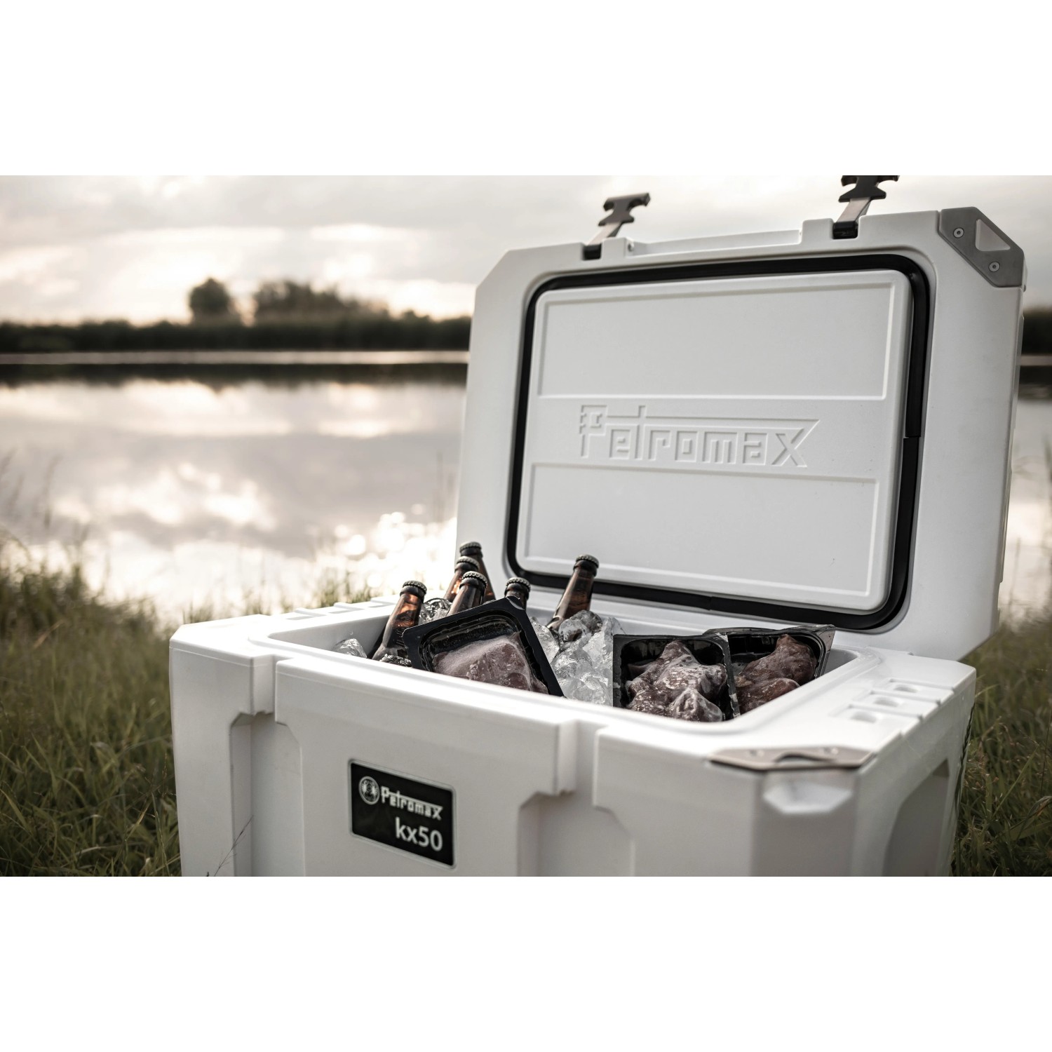 Offene, sandfarbene Petromax Kühlbox 50L mit Getränken und Lebensmitteln. Ideal für Camping.