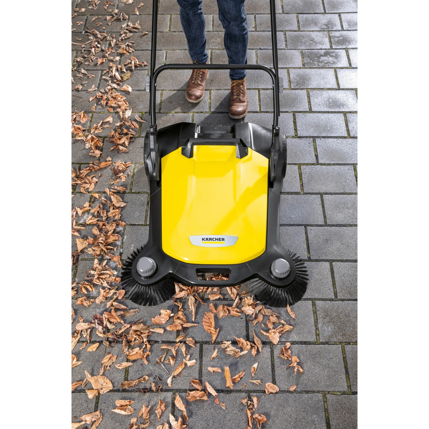 Gelb-schwarze Kärcher Kehrmaschine S6 Twin im Einsatz mit Laub auf Pflastersteinen.