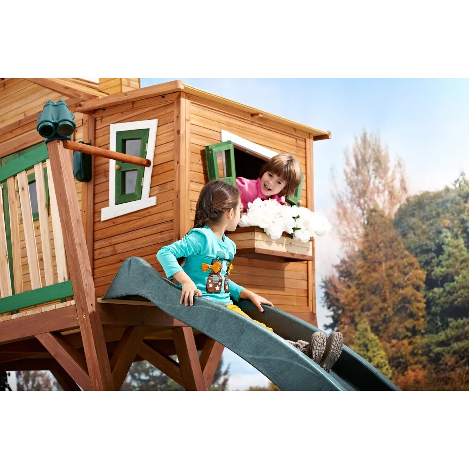 Spielhaus mit Blumenkasten und Kindern am Fenster und auf der Rutsche.