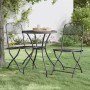 Zwei anthrazitfarbene klappbare Gartenstühle aus Streckgitter im Garten, mit einem Tisch.